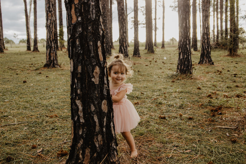 A flower girl wears our Gigi dress in peachy blush.