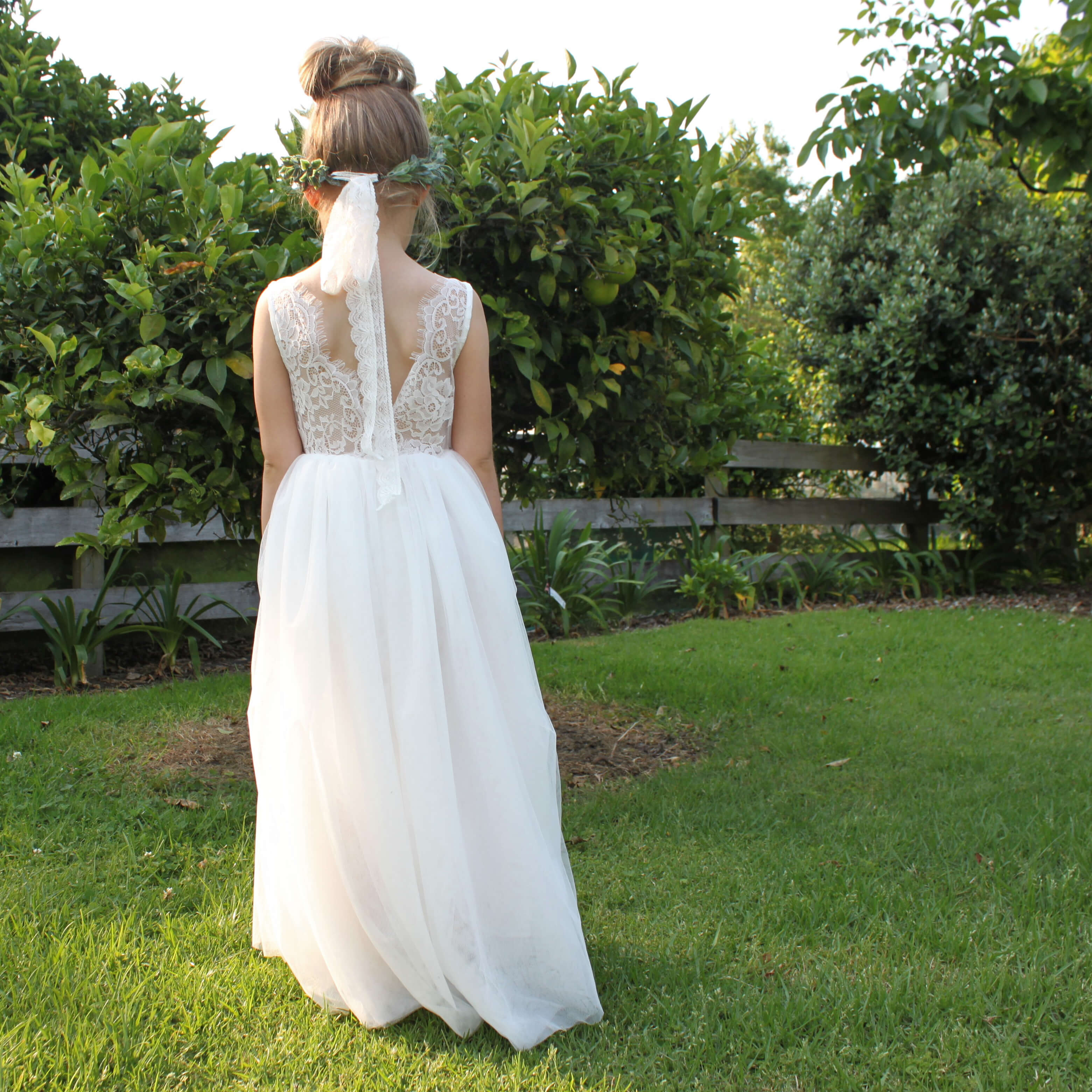 Mia flower girl dress shown from the back on a little girl. Showing the ivory tulle skirt and lace bodice.