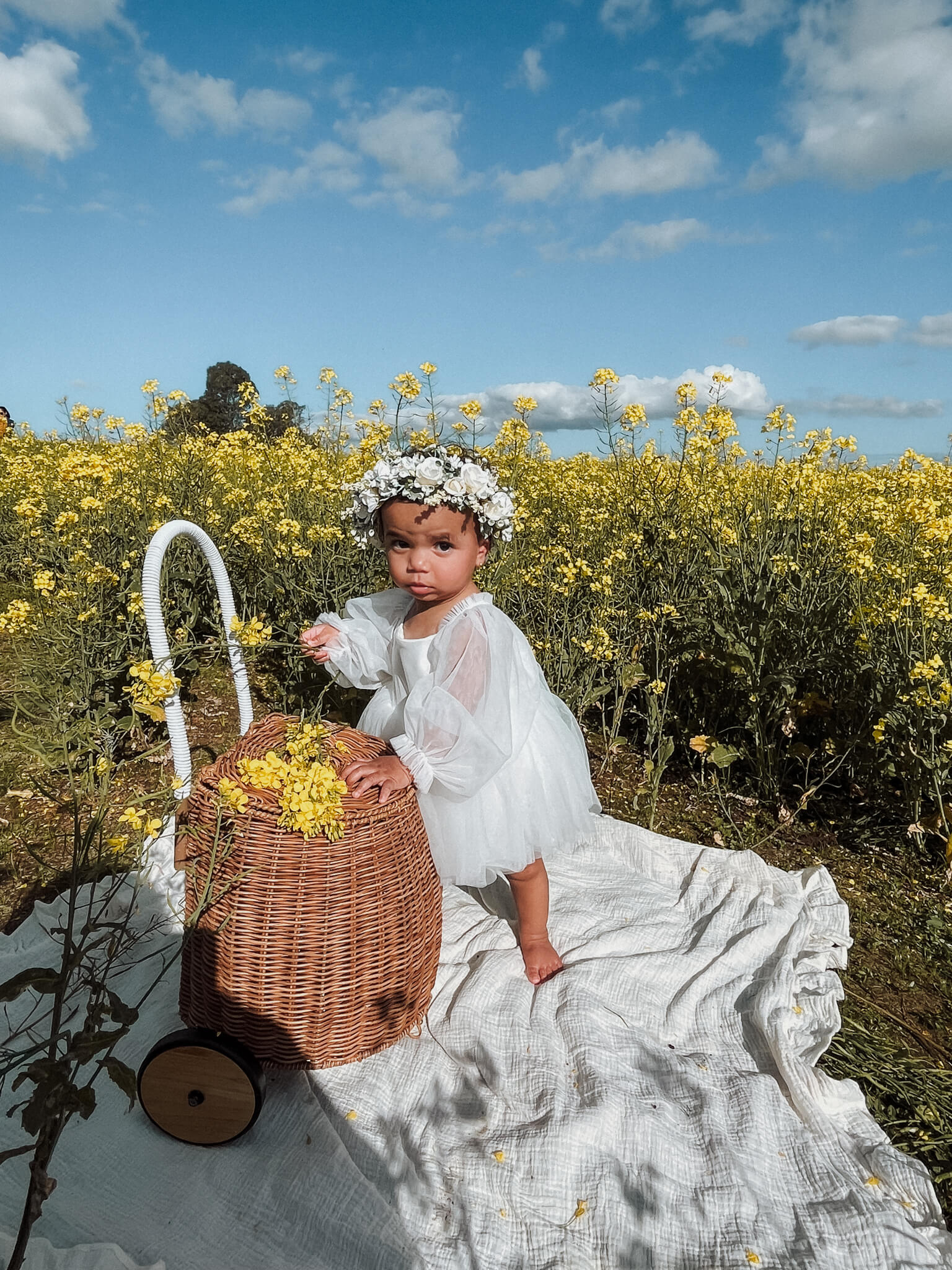 A baby girl wears our Eva baby flower girl dress in ivory.