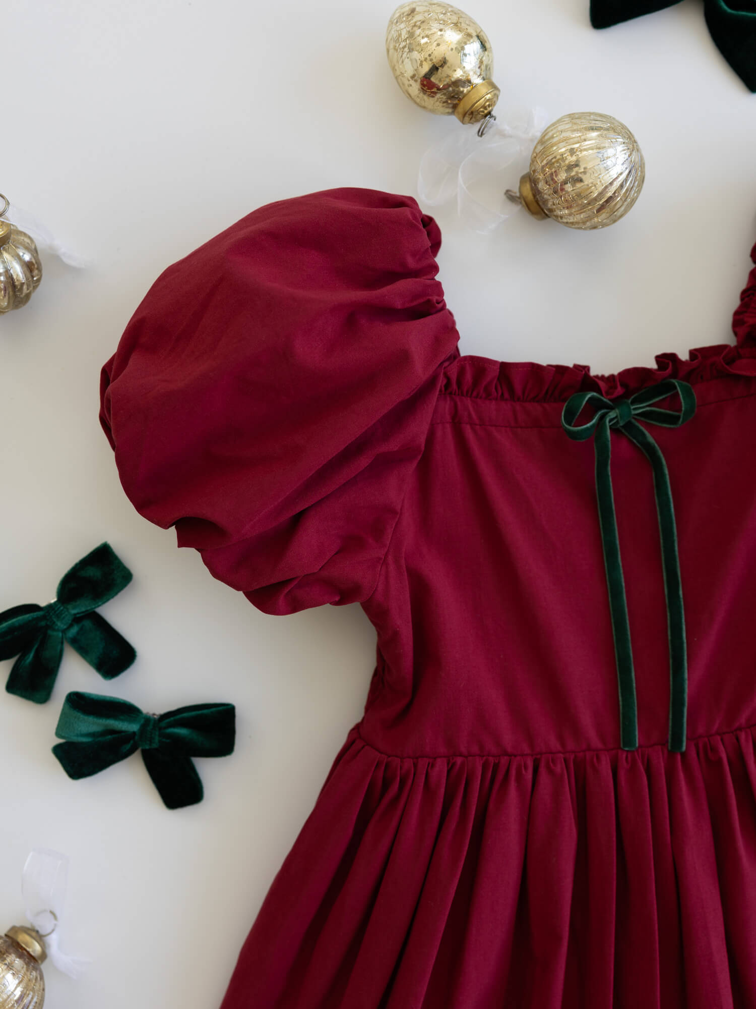 Ava crimson red girls Christmas dress with green velvet bow detail at the neckline.