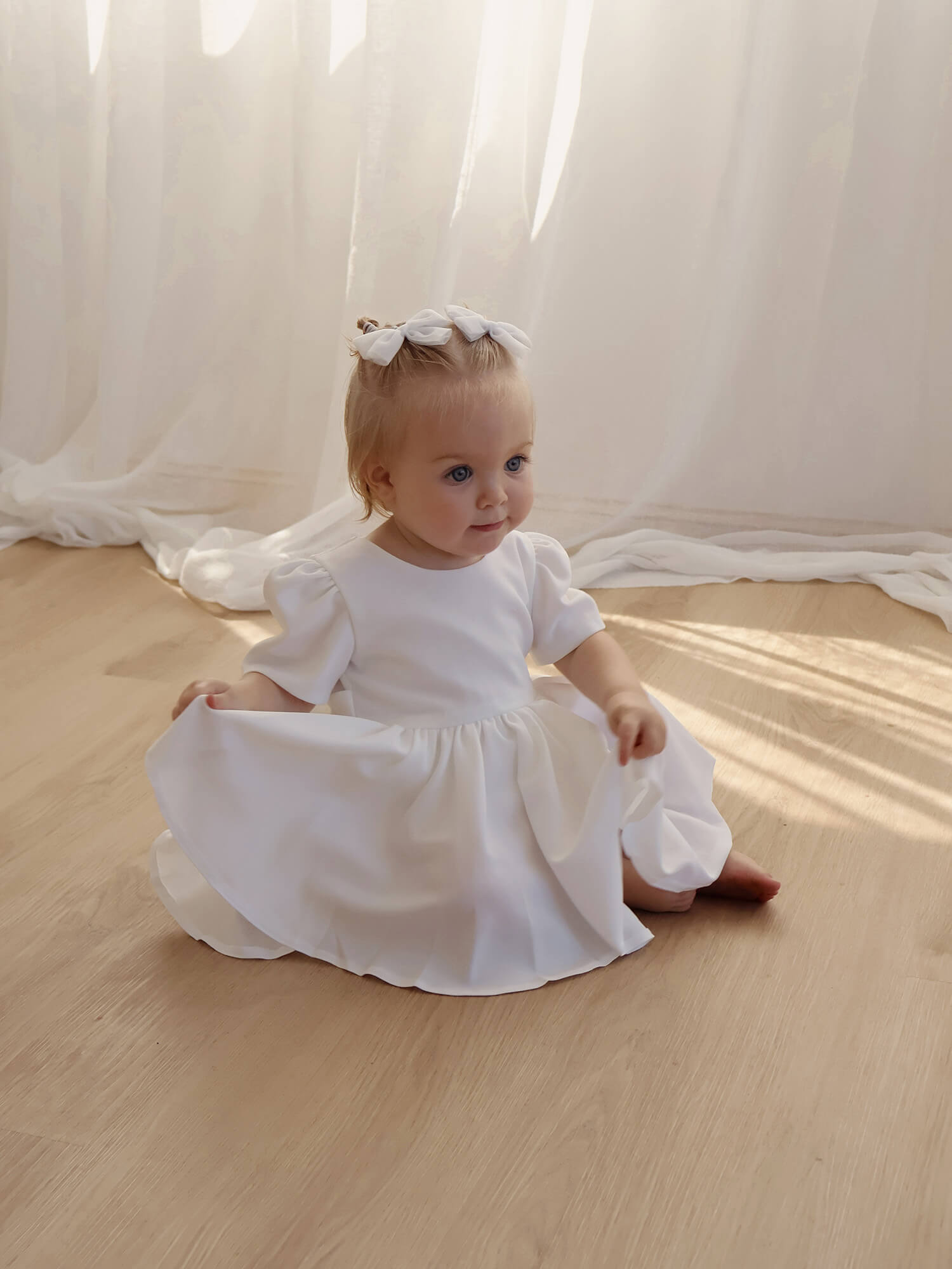 Ivory crepe baby flower girl dress is worn by a baby.