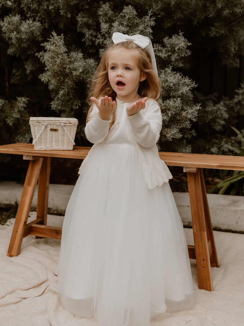 Chloe embroidered flower girl cardigan is worn by a toddler. She wears a tulle flower girl dress and our Adeline satin bow in her hair.