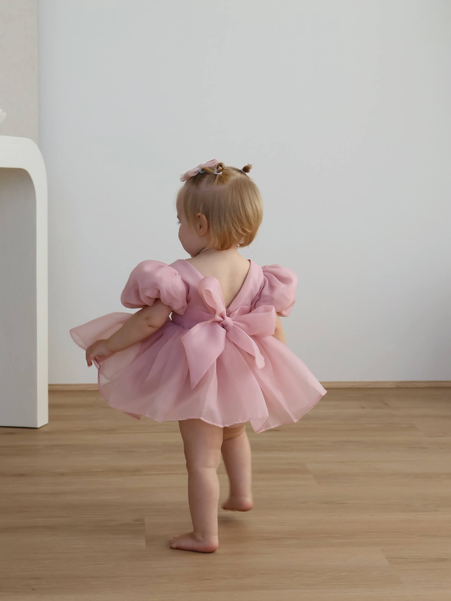 Baby flower girl romper, our Cleo romper in blush, is worn by a toddler.