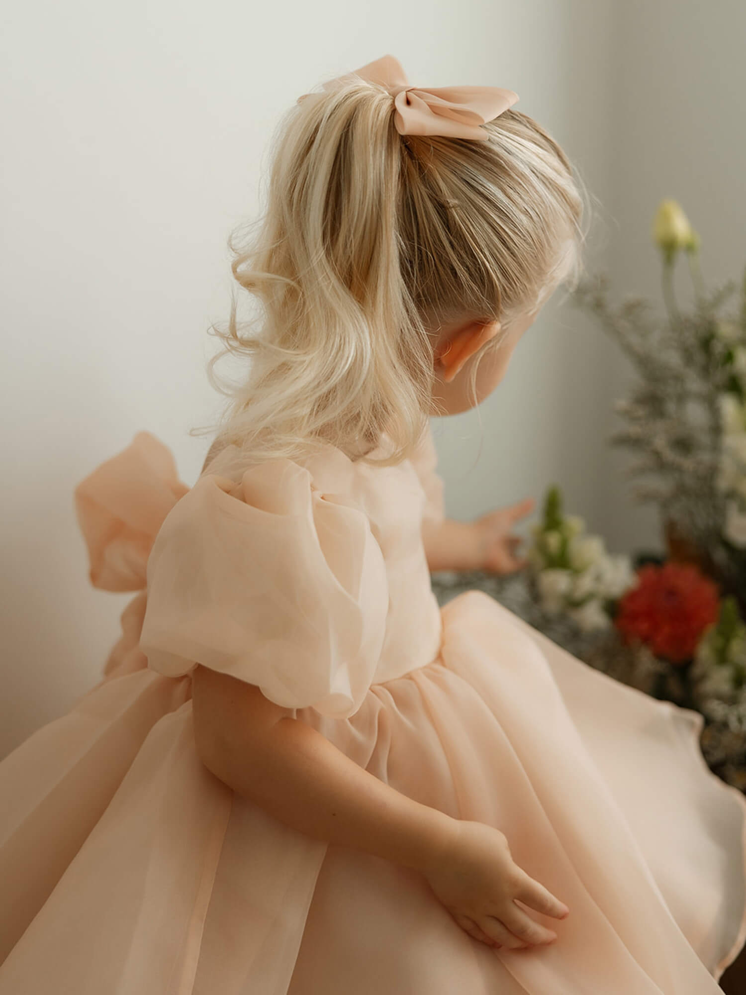 A close up of the puff sleeves on our Cleo champagne flower girl dress, worn by a toddler.