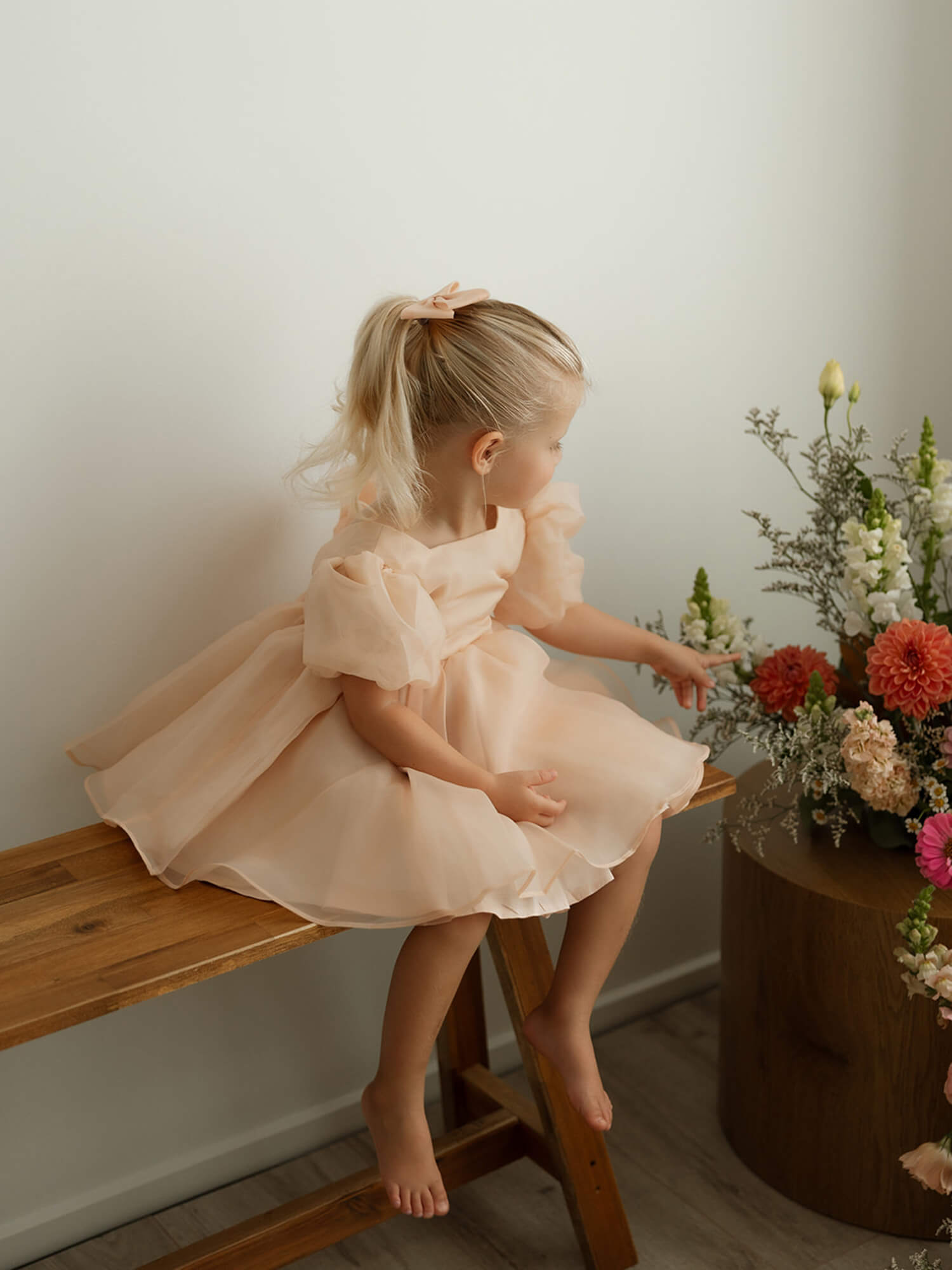 Little girl dressed in our champagne Cleo flower girl gown, perfect for weddings.