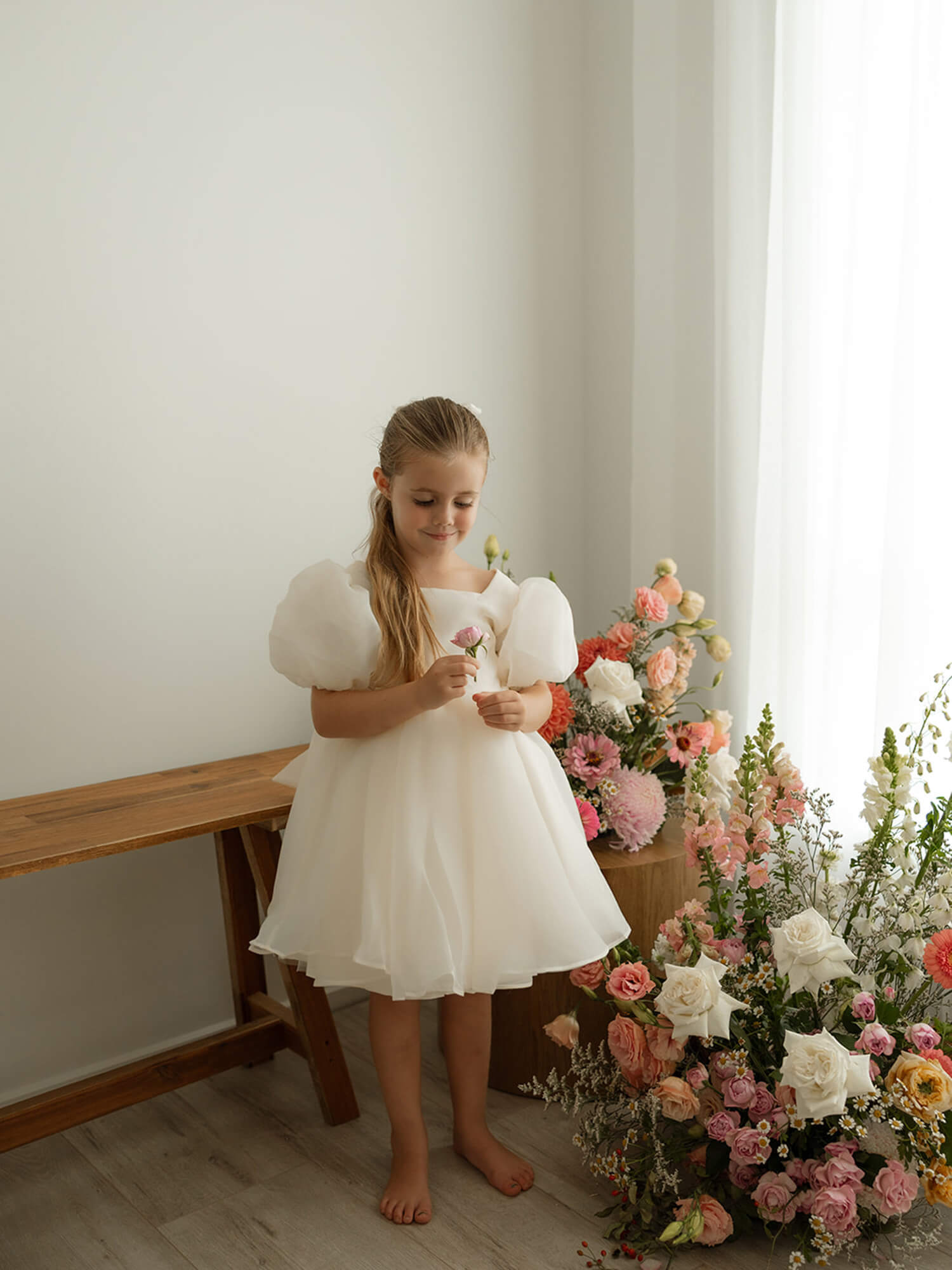 Flower girl wearing our Cleo cream organza dress with classic puff sleeves.