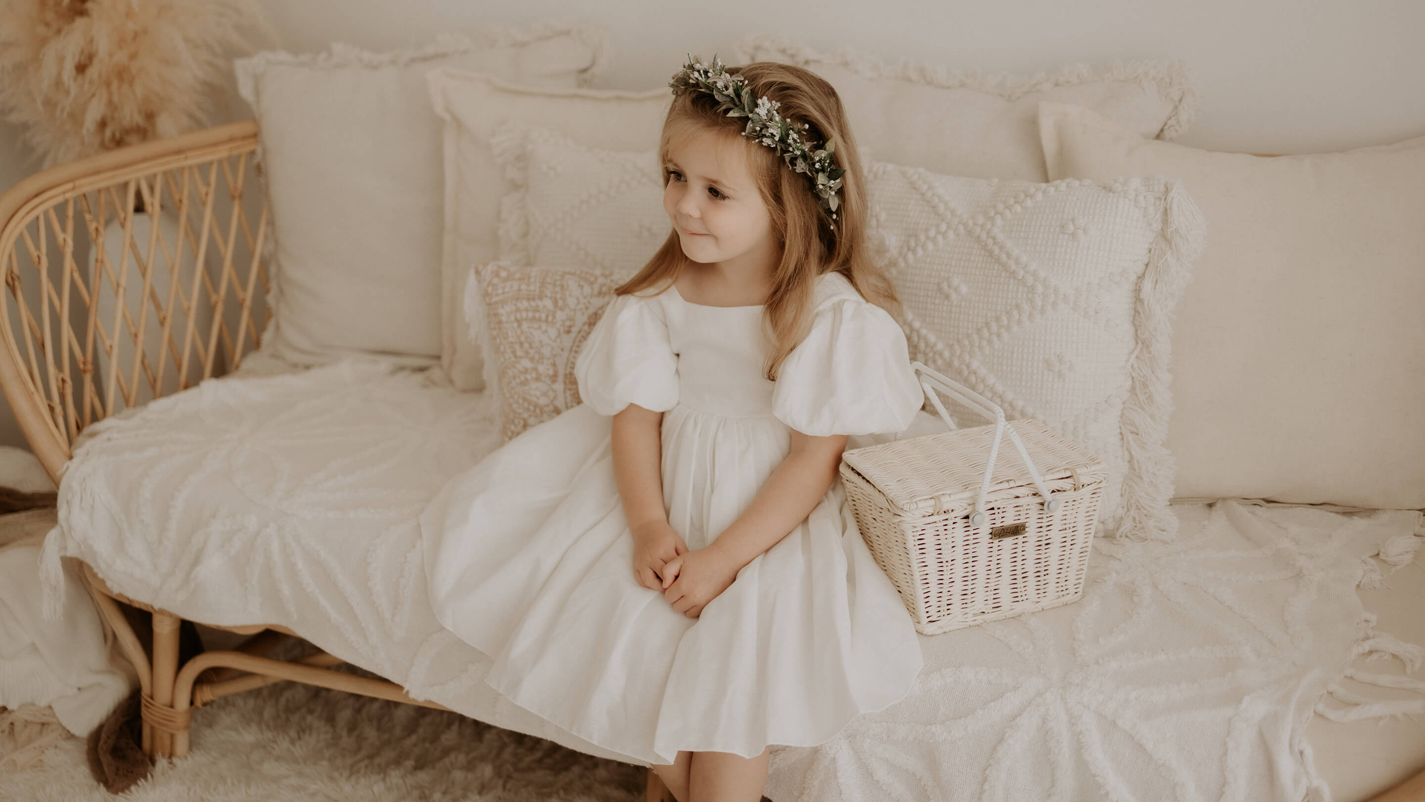 Flower girl sits wearing our Cleo linen puff sleeve flower girl dress, and Blythe girls flower crown.
