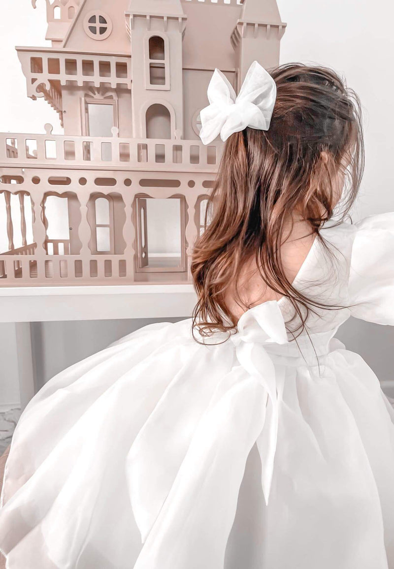Cleo puff sleeve flower girl dress shown from behind on a young flower girl. She also wears a tulle bow hair clip.