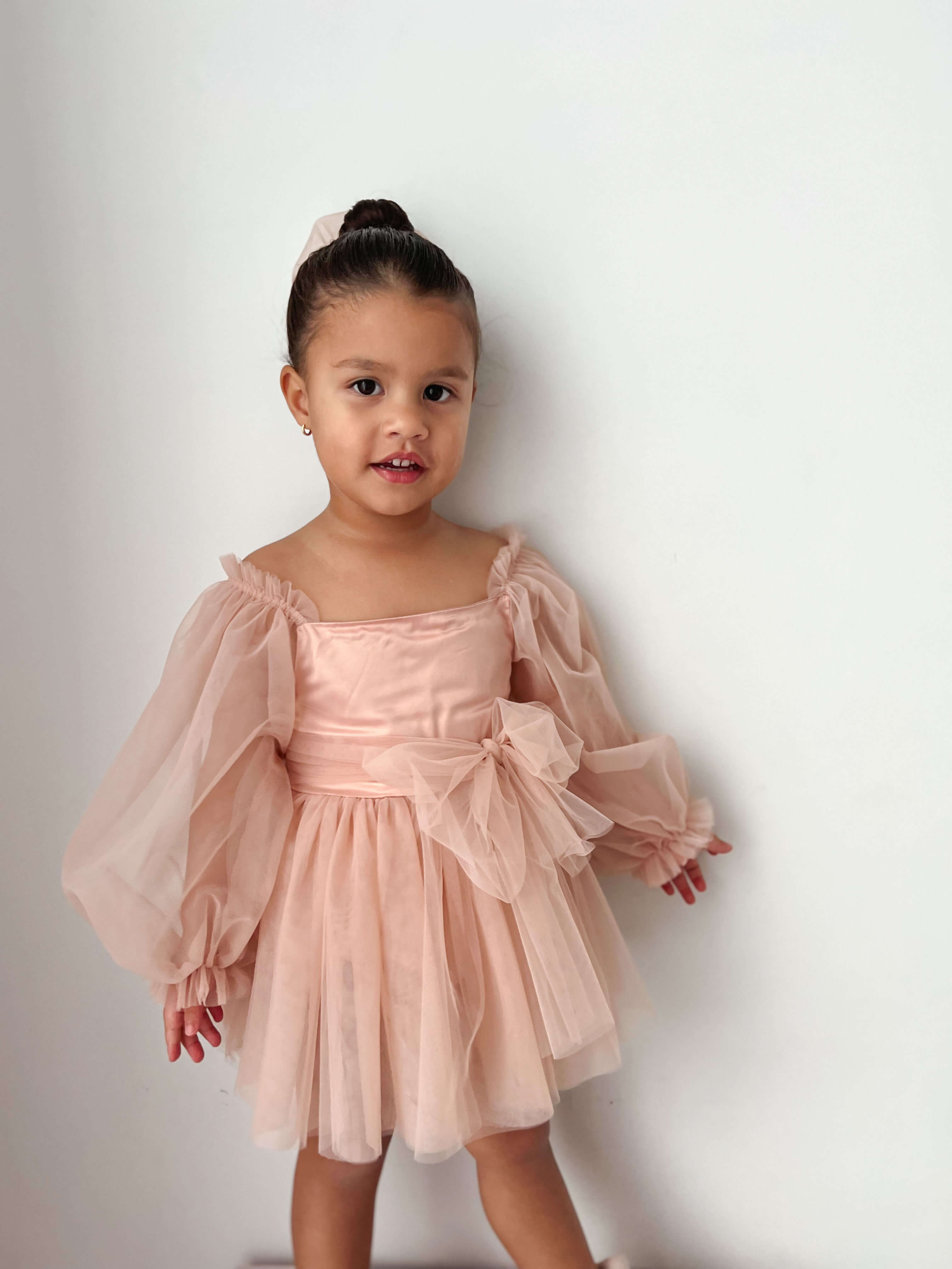 Champagne Eva flower girl romper is worn by a young girl.