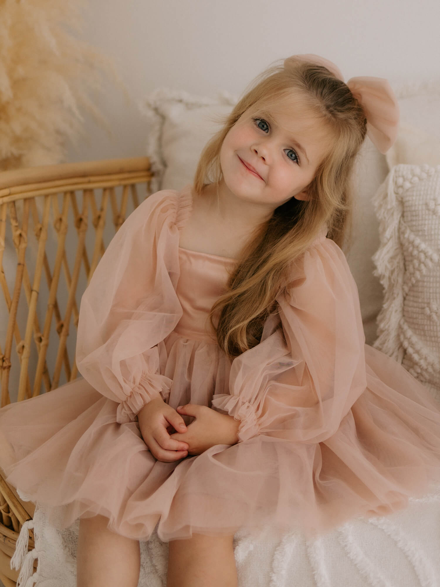 Champagne Eva flower girl dress is worn by a young flower girl, she also wears a tulle bow in her hair.