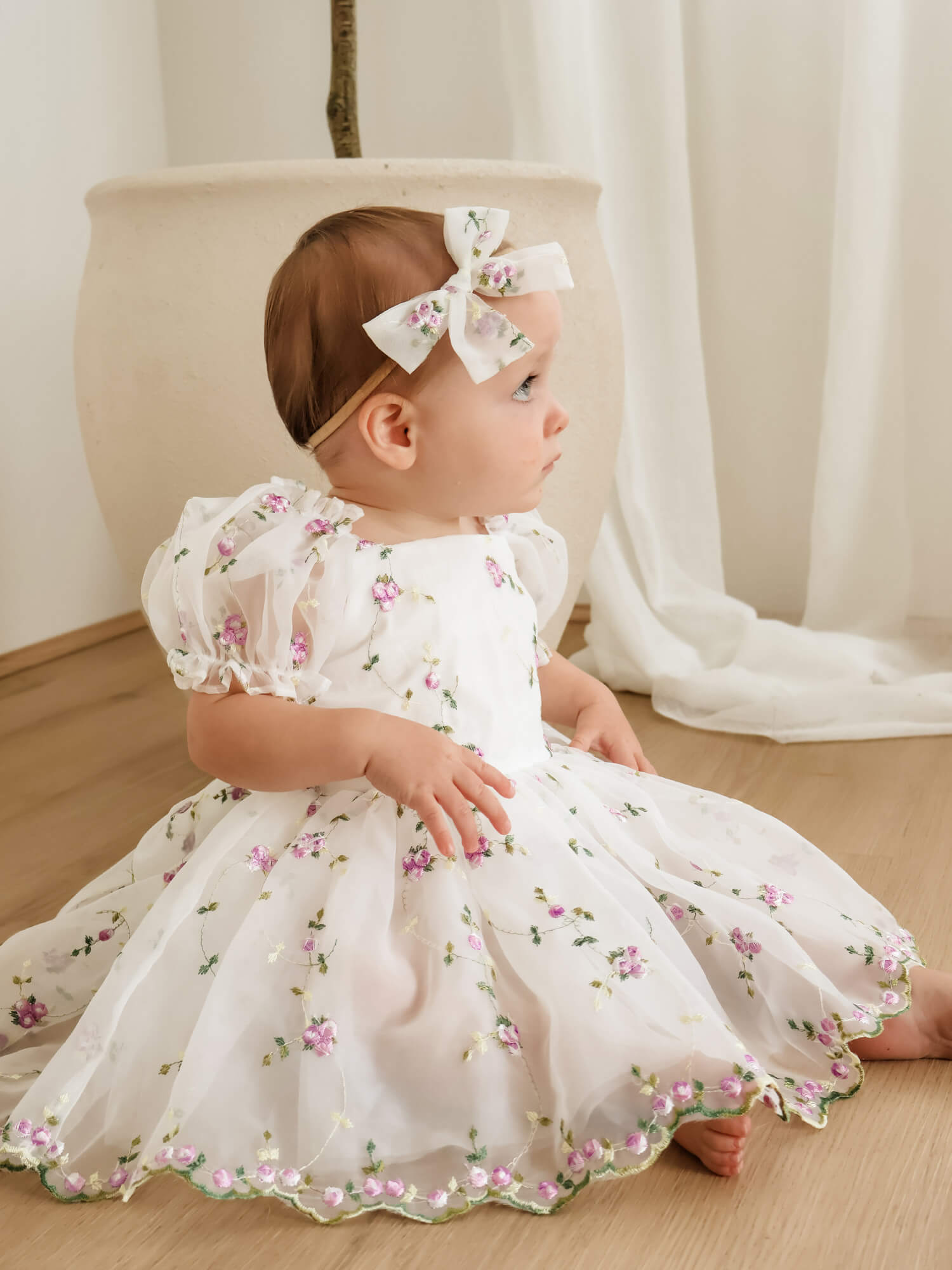 Fleur lilac baby flower girl romper and baby bow headband is worn by a toddler.