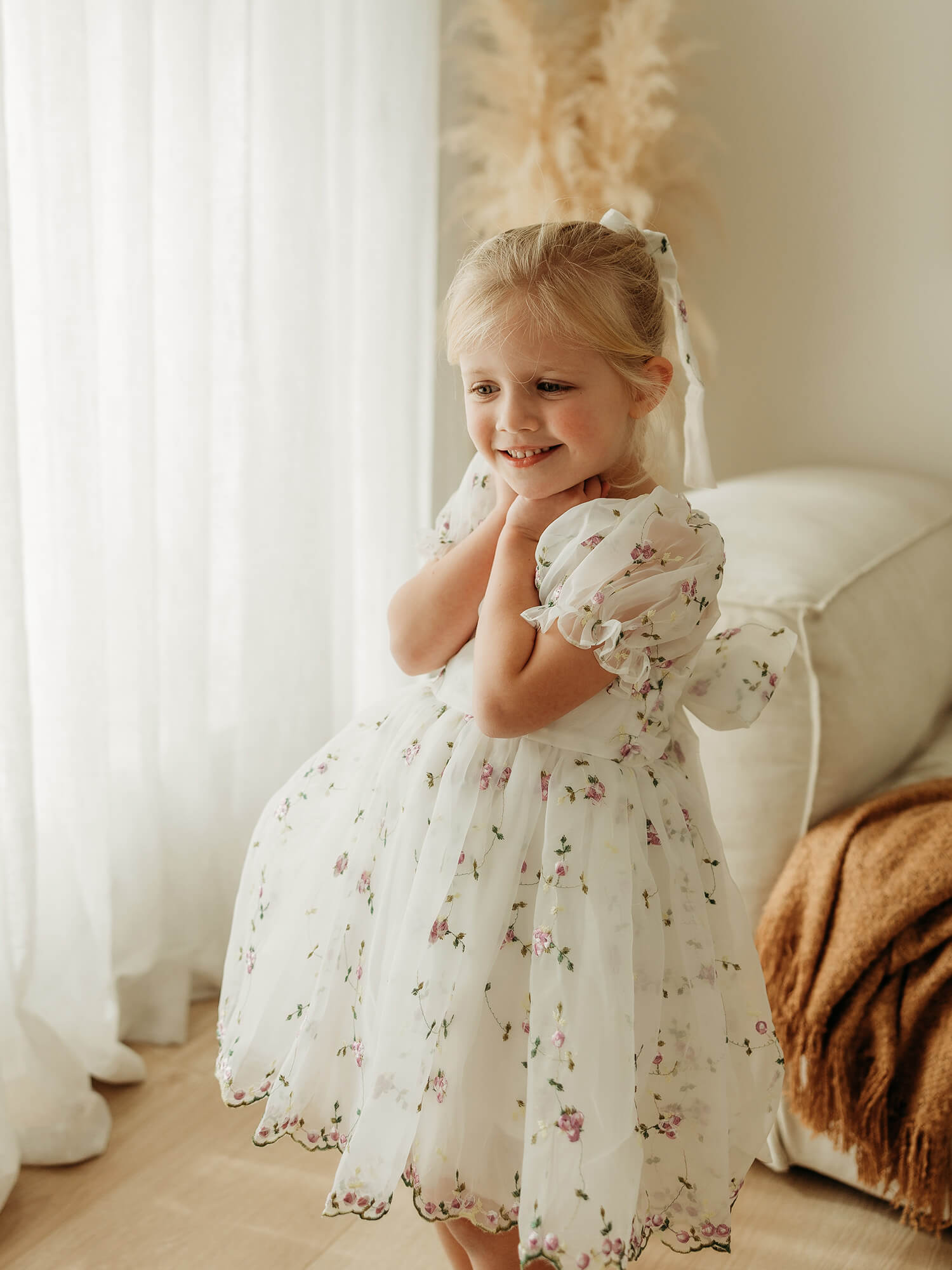 A young girl wears our Fleur organza flower girl dress with lilac floral pattern.