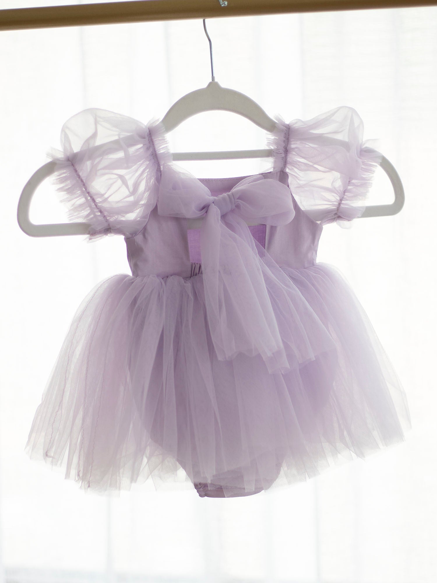 Gabrielle lilac tulle baby romper from the back, showing the tulle bow detail and soft tulle puff sleeves.