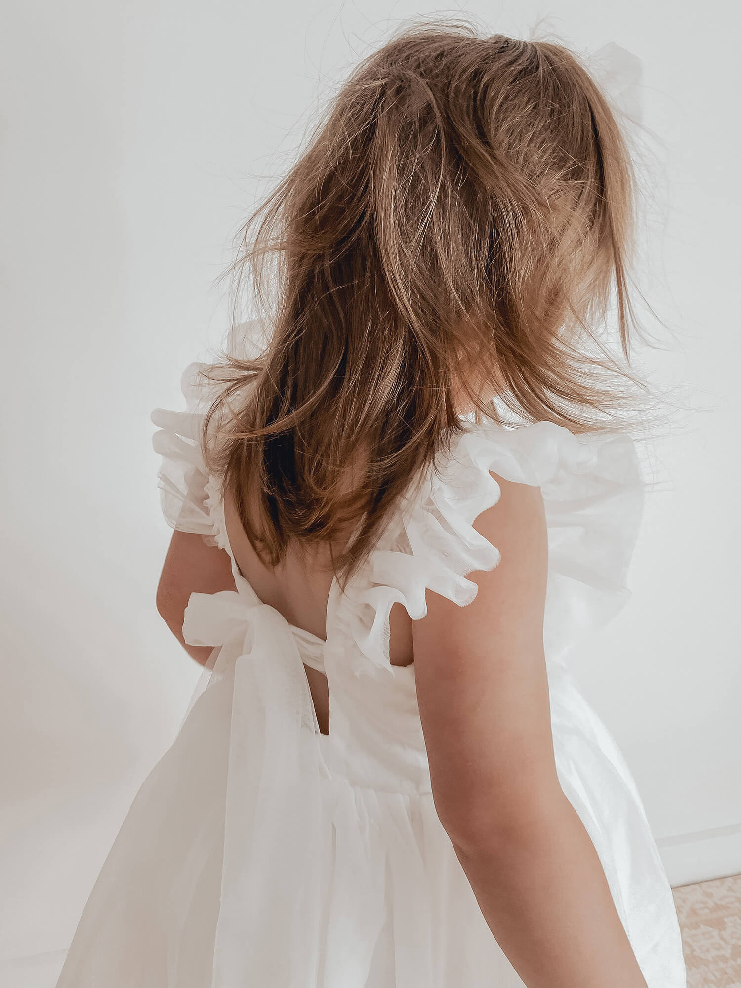Gigi ivory flower girl dress shown from behind, showing the tulle flutter sleeves and tulle bow at the back.