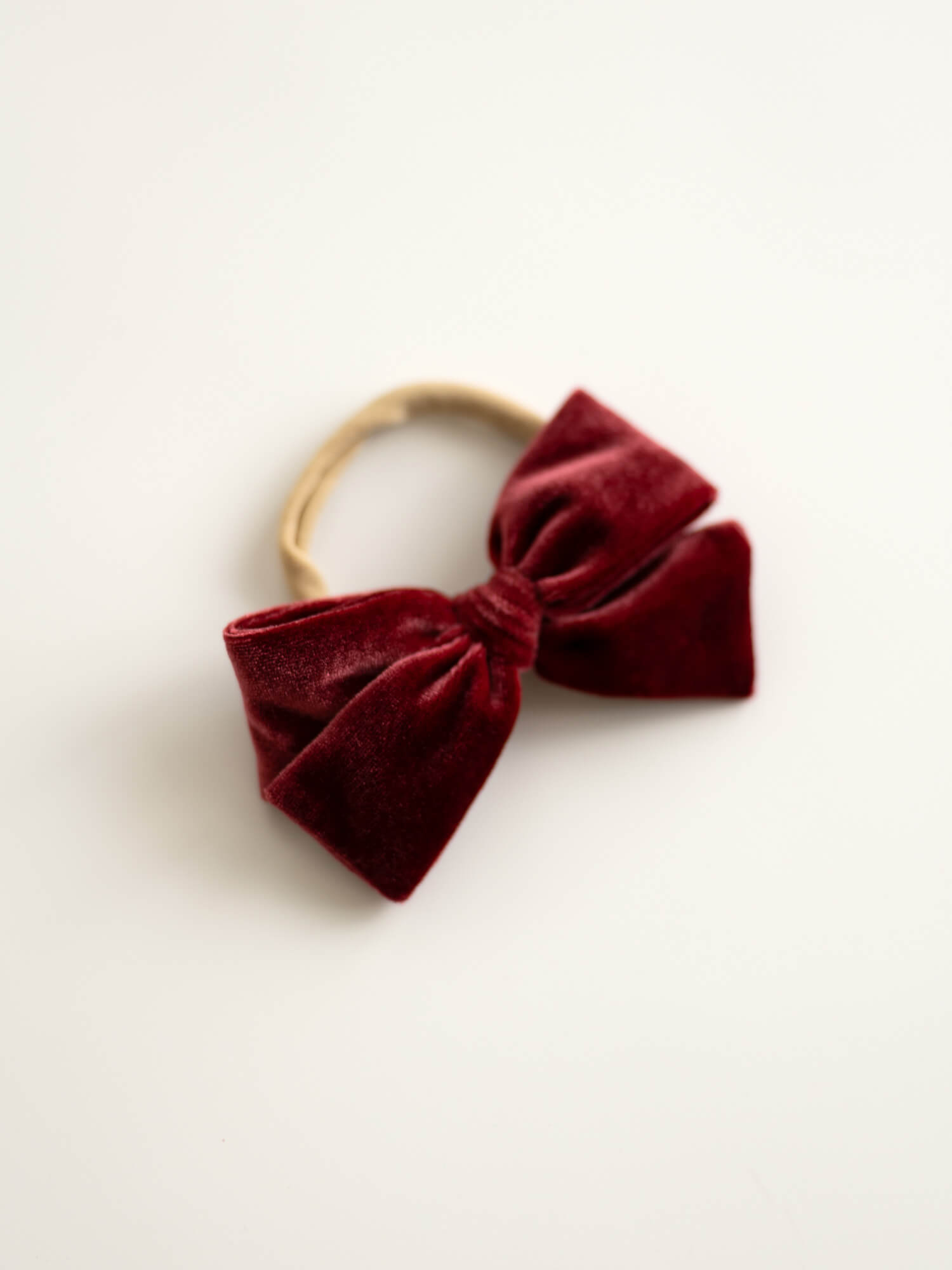 Crimson velvet hair bow on a soft headband for babies.