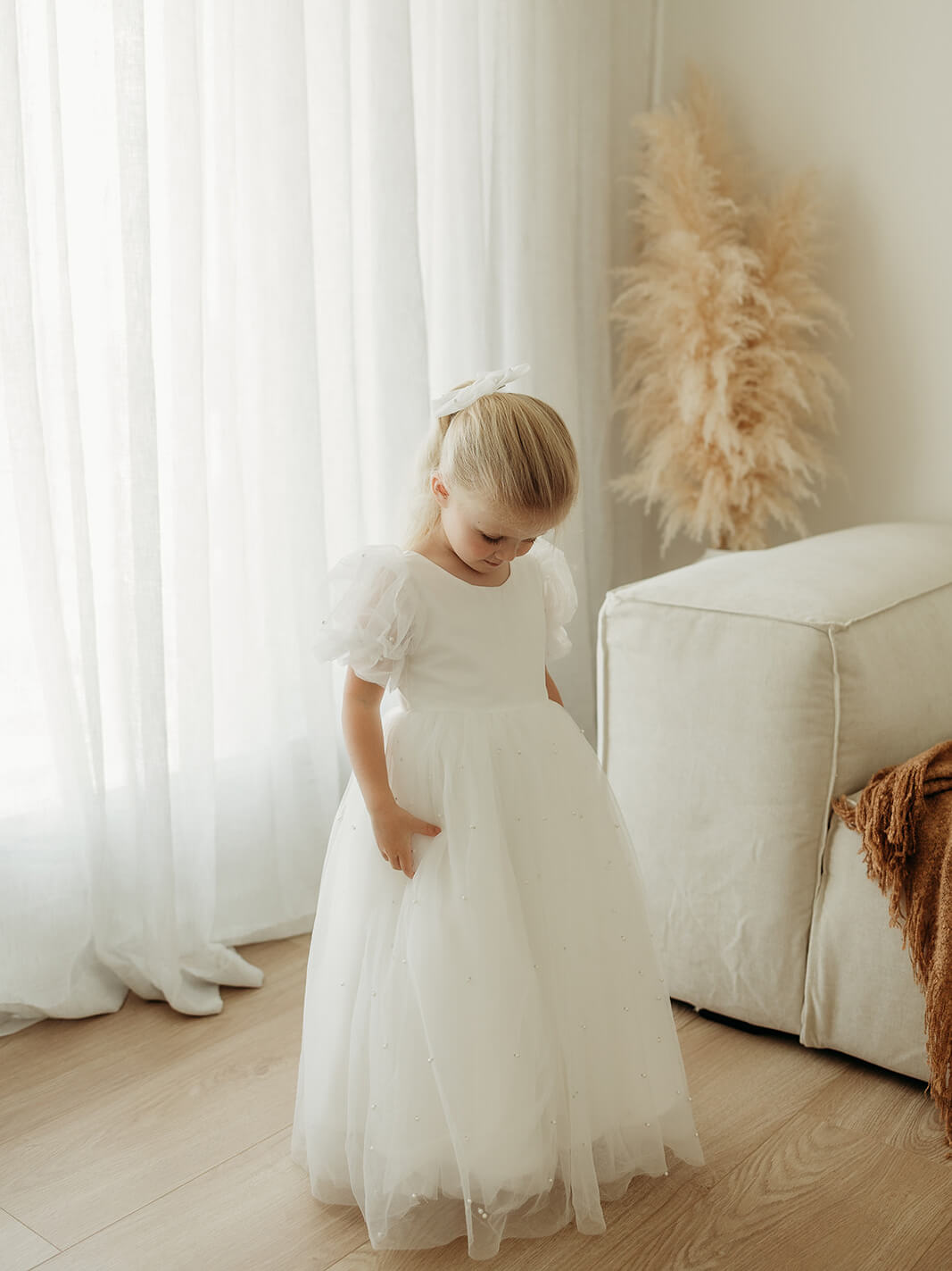 A little girl wears our full length Gracie flower girl dress, with pearl beading on the skirt and sleeves.