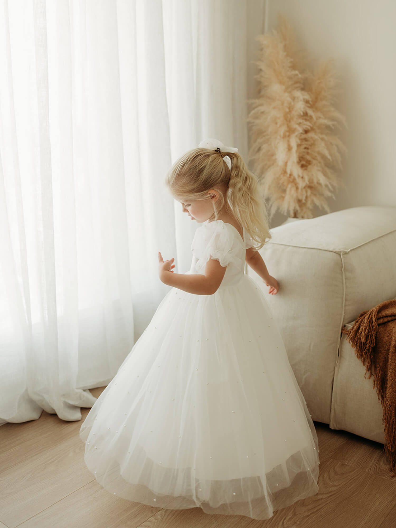A young girl twirls wearing our Gracie beaded flower girl dress in ivory.