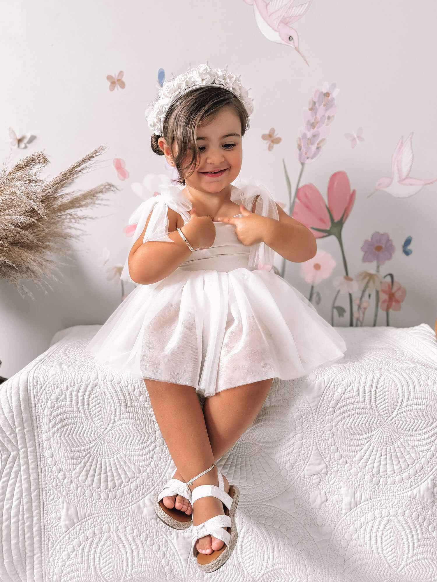 A toddler smiles wearing our Harper flower girl romper.
