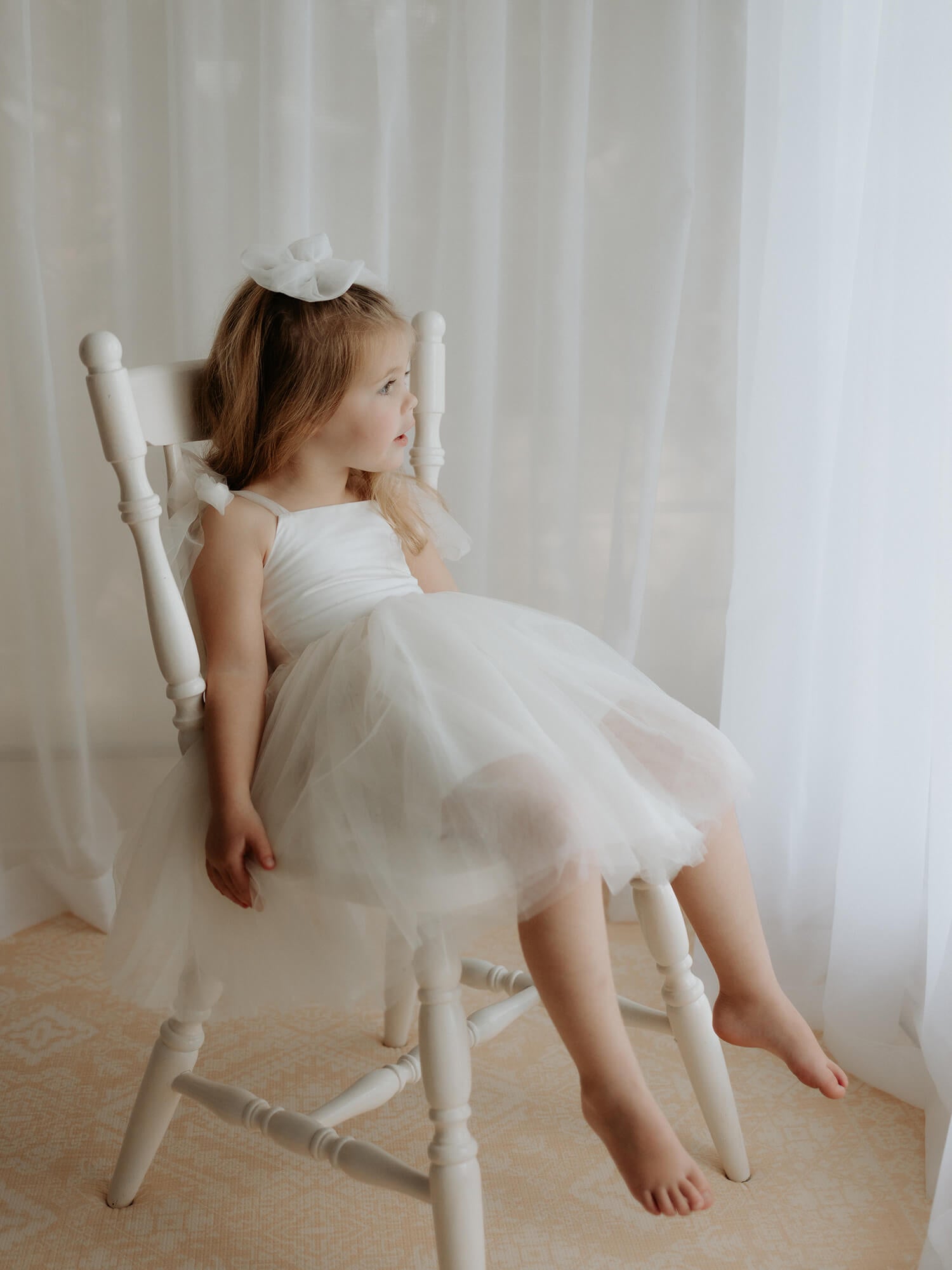 A young flower girl wears our Harper tea length flower girl dress in cream.