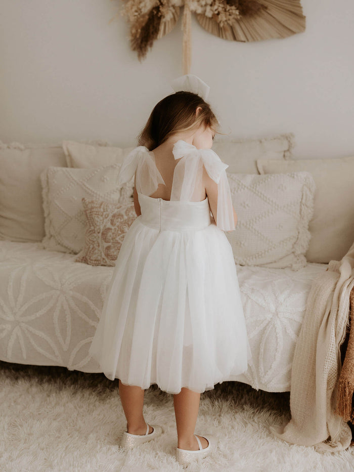 Isla ivory flower girl dress with tulle tie sleeves is shown from the back.