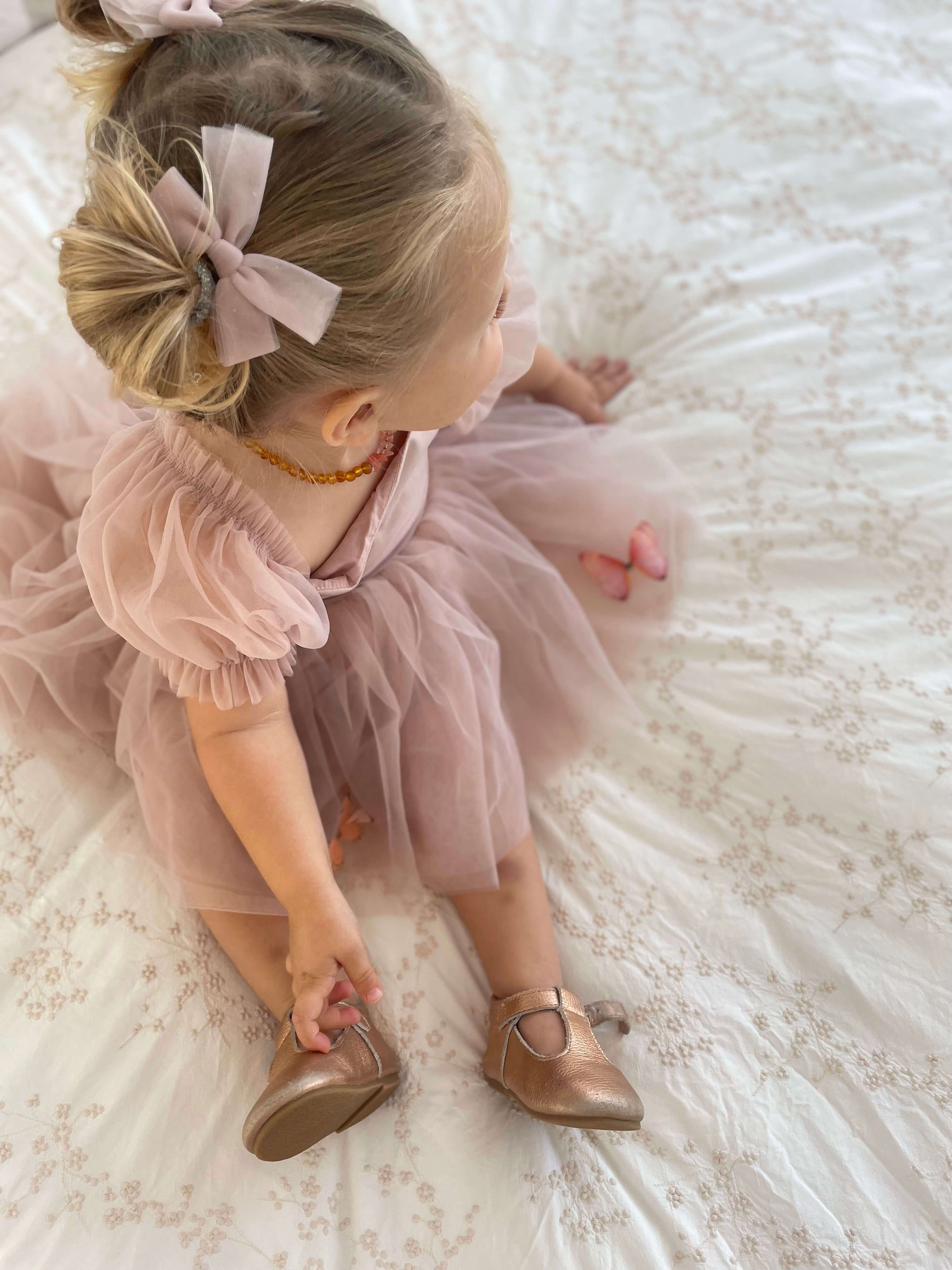 Layla dusty pink baby flower girl dress is worn along with matching tulle pigtail hair bows.