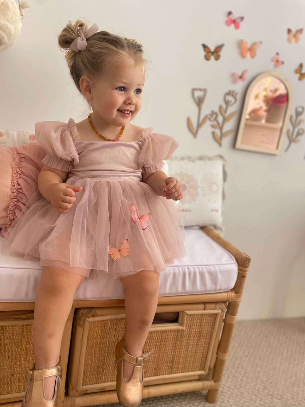 Layla baby flower girl dress in dusty pink is worn by a toddler. She also wears our matching tulle pigtail bows in dusty pink.