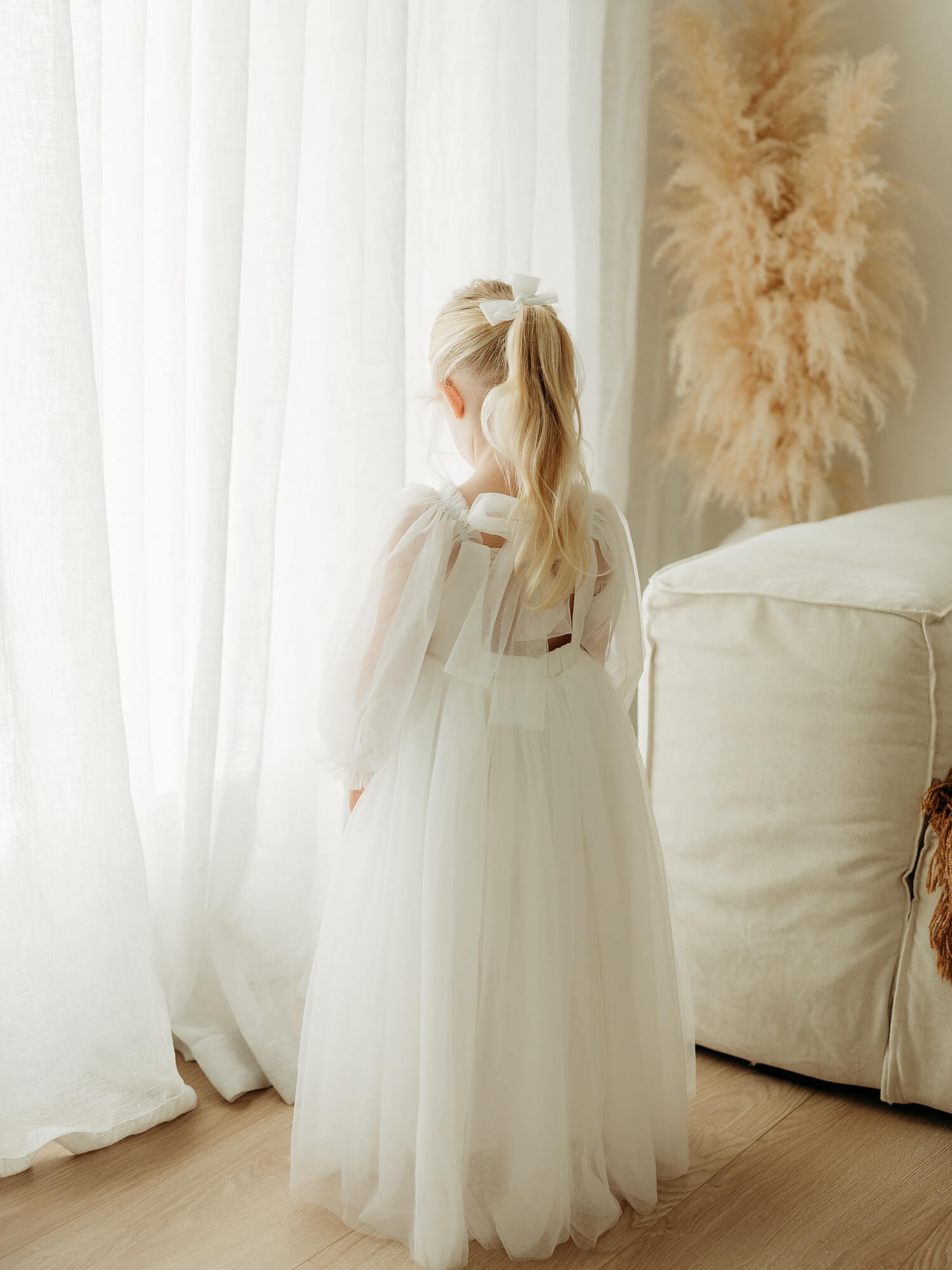 Young girl in a full length tulle flower girl dress in ivory.