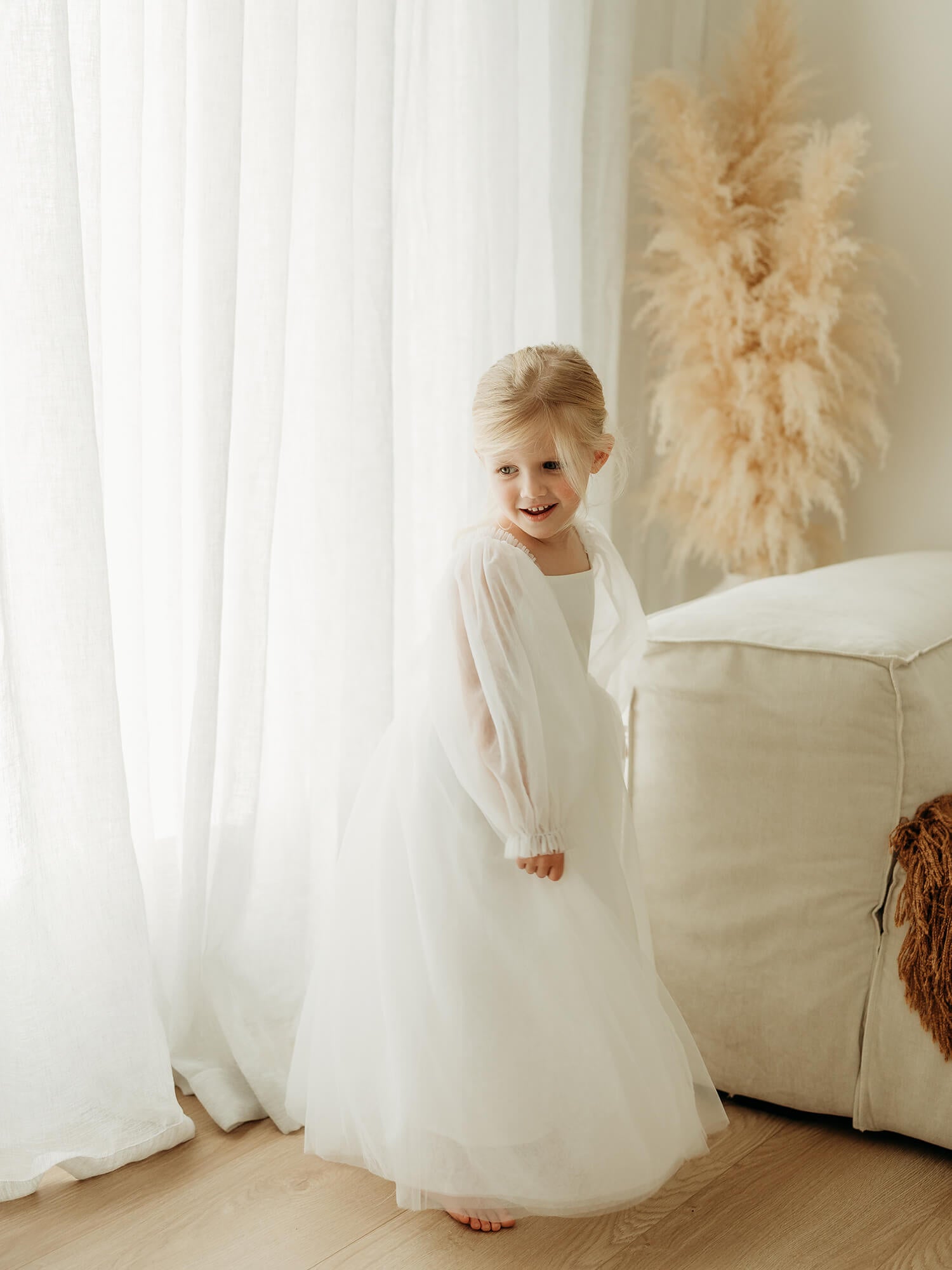 Ivory tulle flower girl dress is worn by a young girl who is twirling.