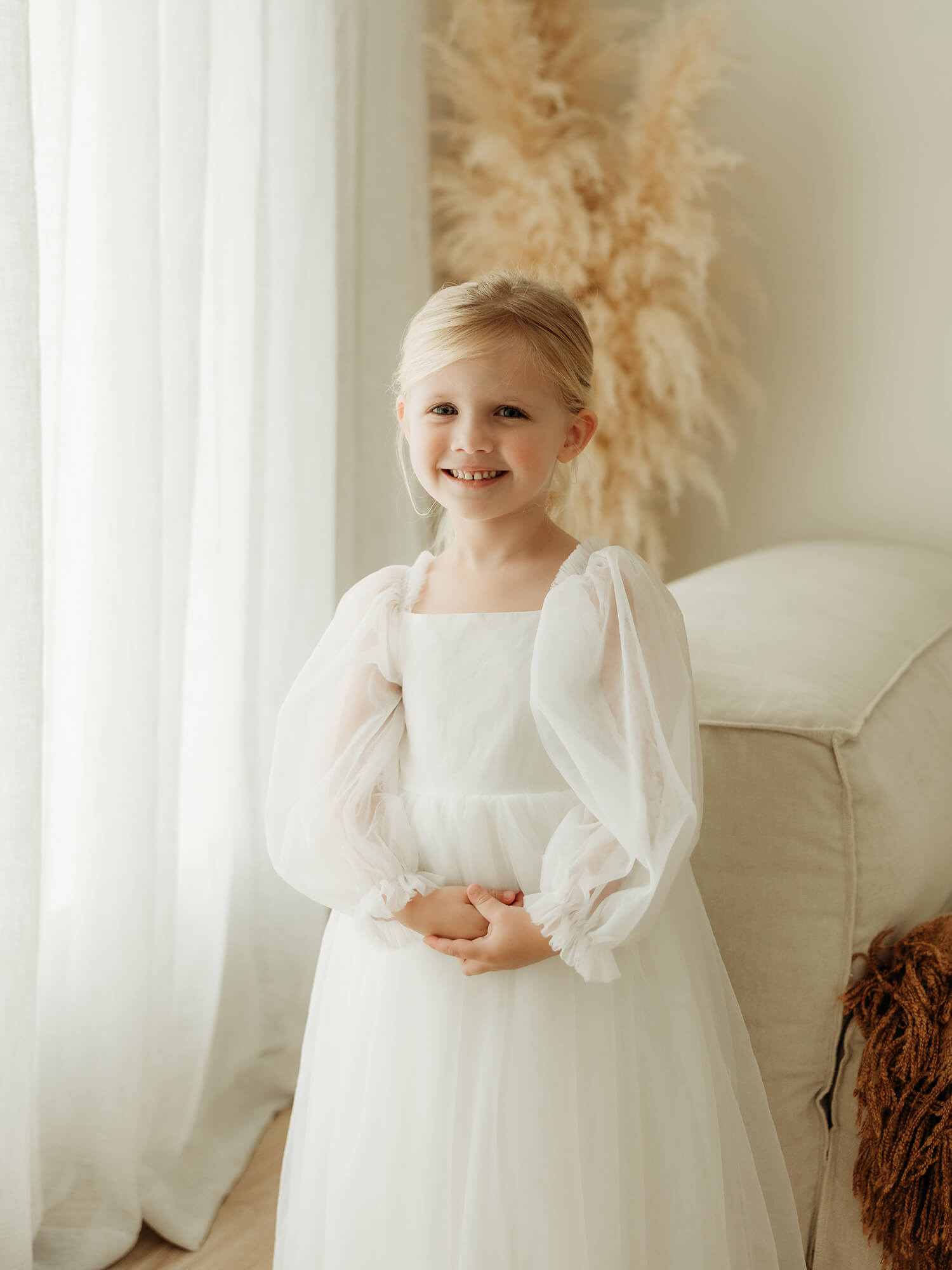 Wren ivory full length flower girl dress is worn by a young girl.