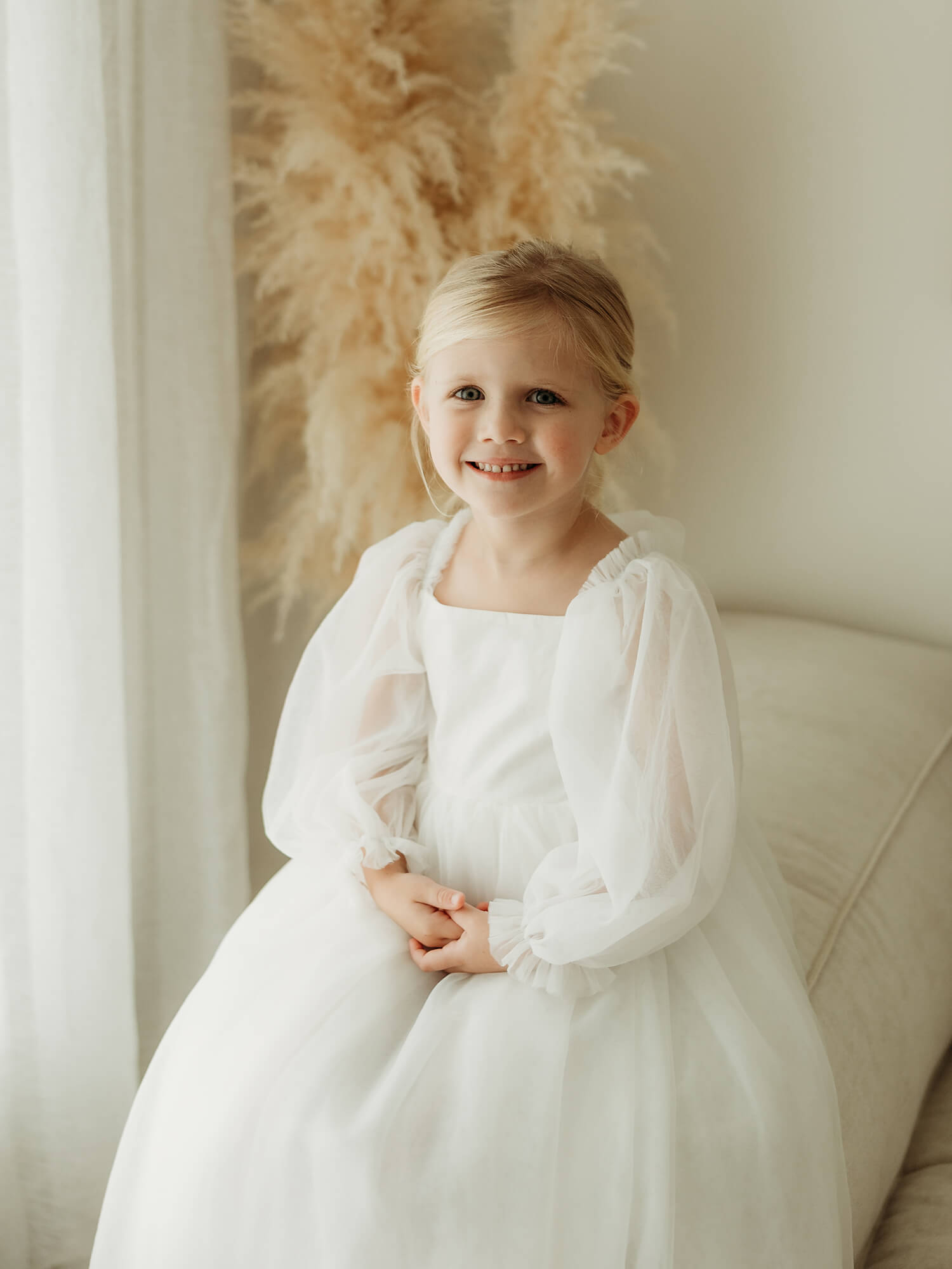 Ivory tulle sleeve flower girl dress is worn by a young girl.