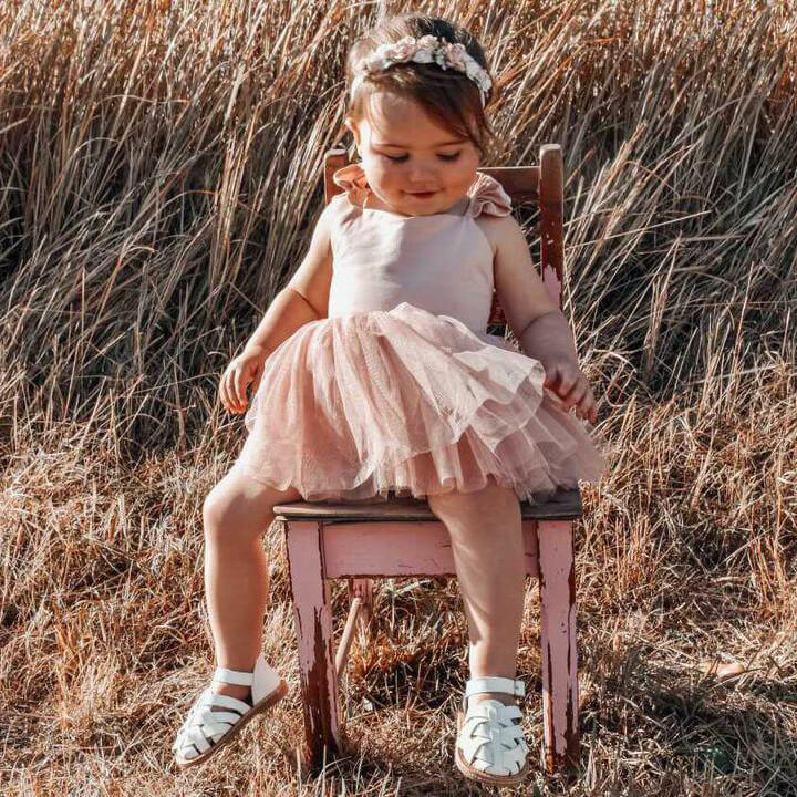 Toddler wears our baby floral headband in dusty pink and our Everly tulle romper.