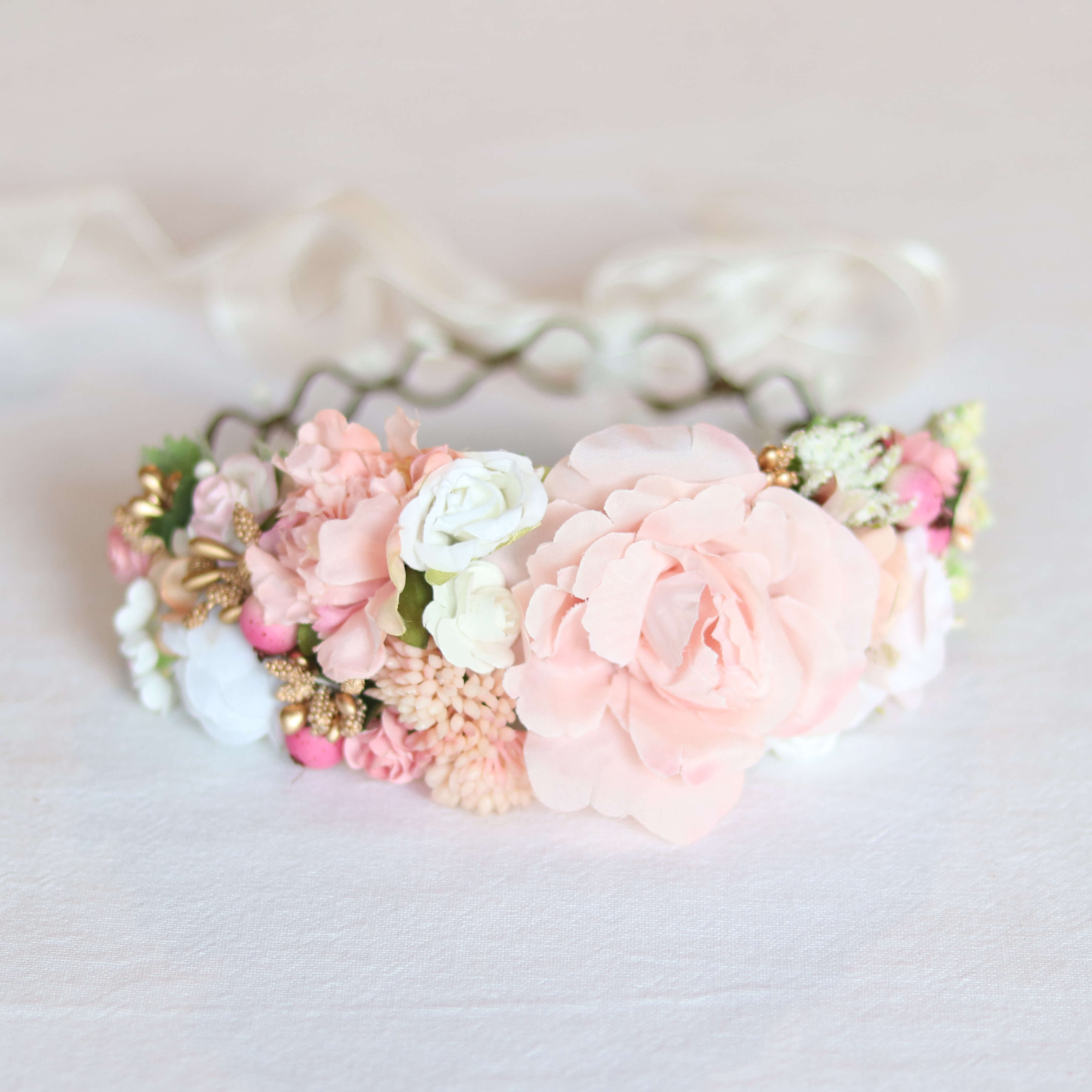 Aria girls peach flower crown shown from the front, showing a main large peach bloom and smaller flowers around it.