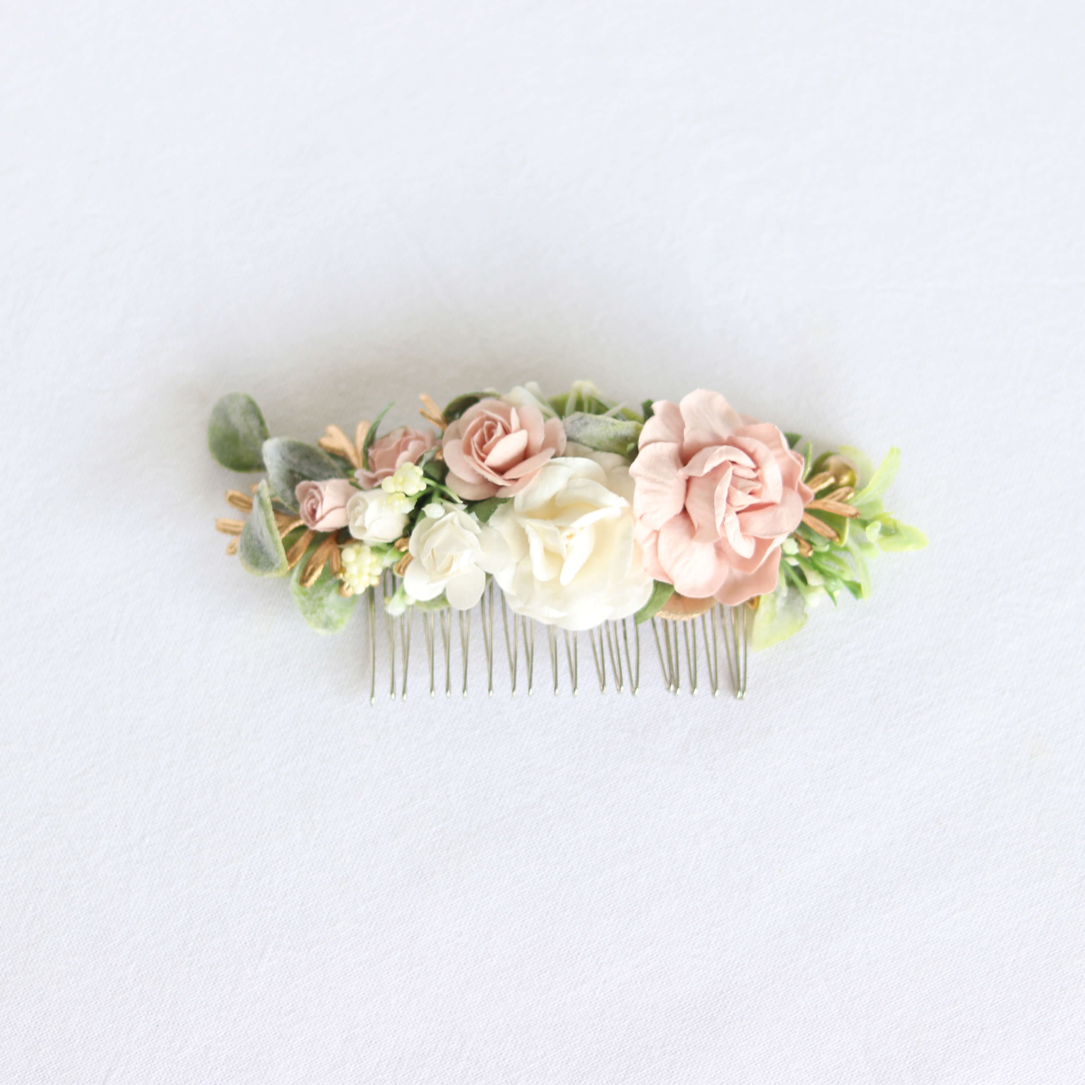 Emma girls floral hair comb accessory, showing ivory and dusty pink flowers, with greenery and gold accents upon a silver hair comb.