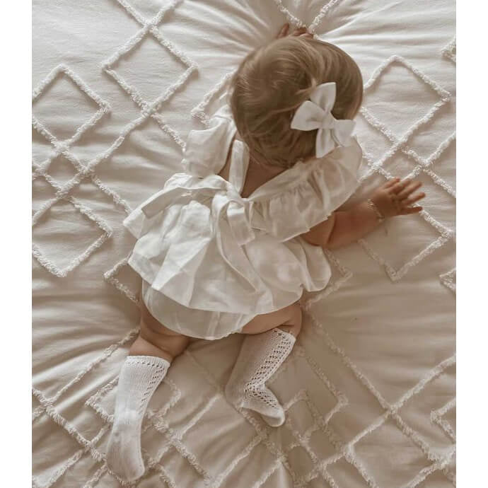 Baby girl wears our Olive linen romper and matching bow clip in her hair.