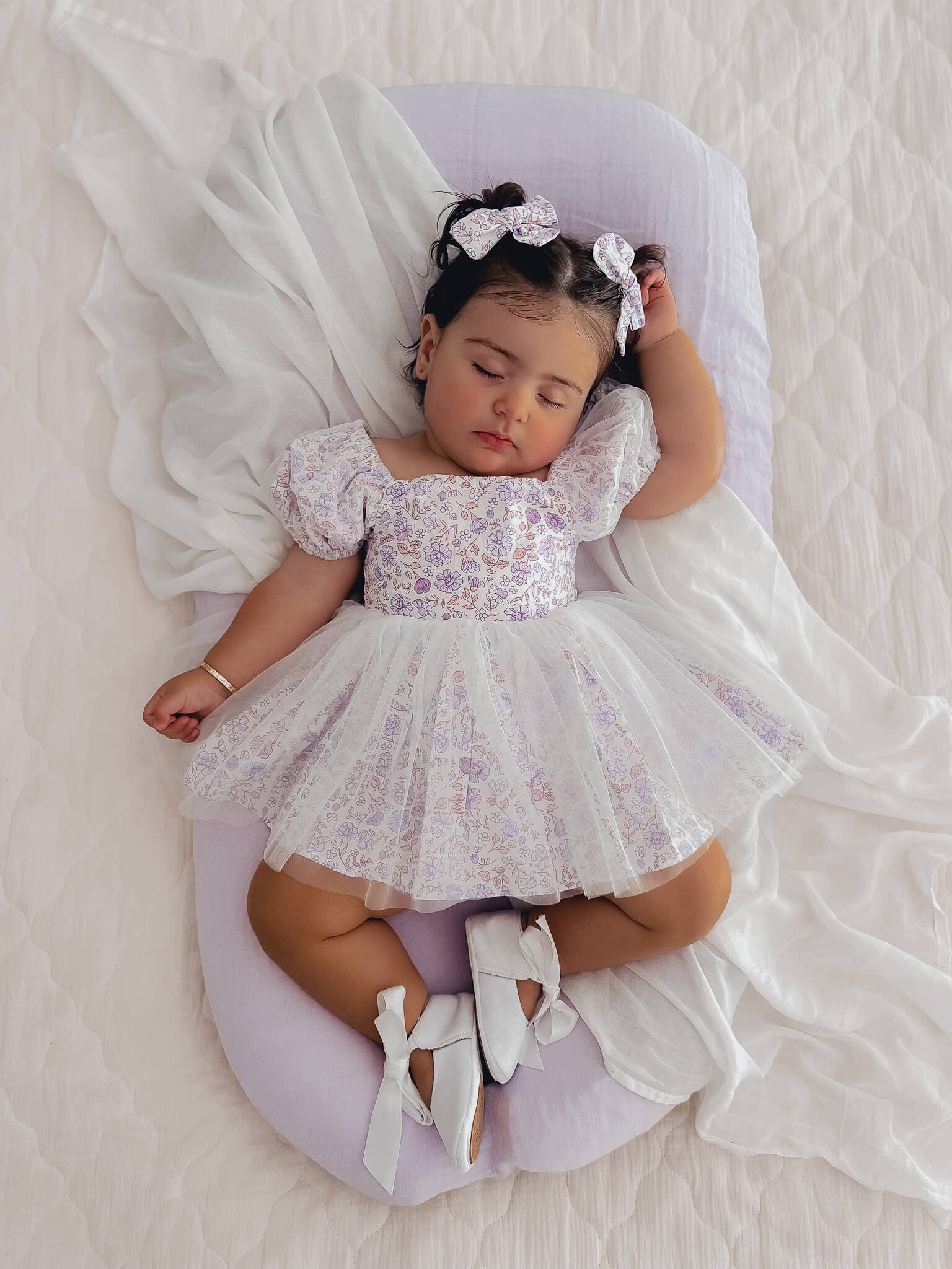 Baby girl sleeps wearing a tulle baby romper.