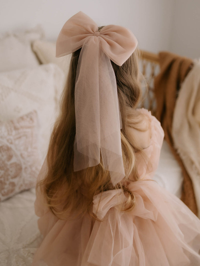 Large champagne tulle bow is worn by a young girl, along with our Eva champagne flower girl dress.