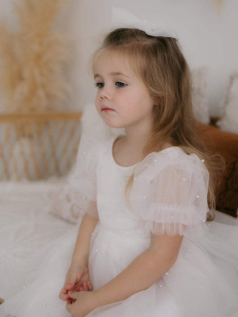 Harper ivory tea length flower girl dress is worn by a young toddler girl. She also wears our Luna flower crown.