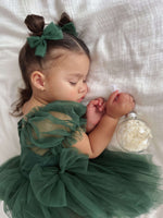 A baby sleeps wearing our emerald green Layla baby dress romper.