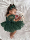 A baby sleeps holding a teddy bear, she wears our Layla emerald green tulle baby romper and matching tulle bow hair clips.
