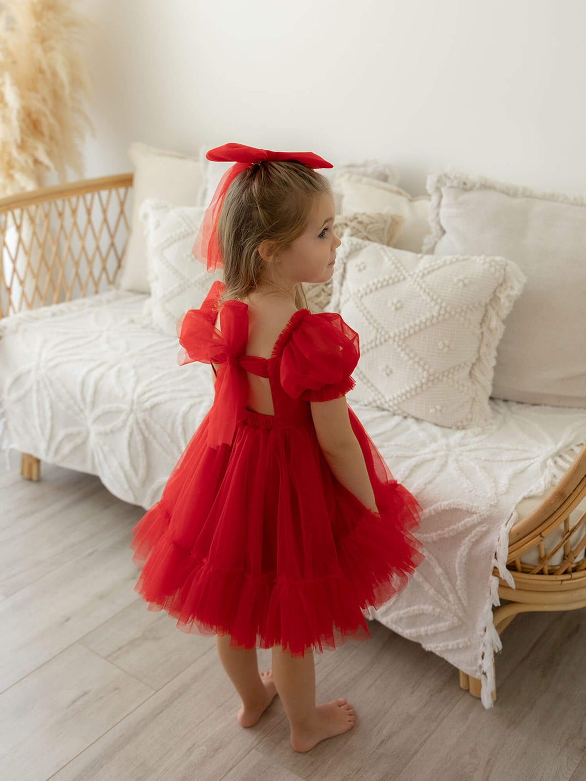 Gabrielle Christmas and flower girl dress in ruby red is worn by a young girl.