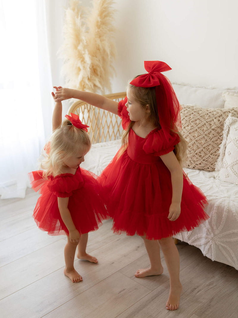 Sisters twirling in matching red Christmas dress and hair bows.