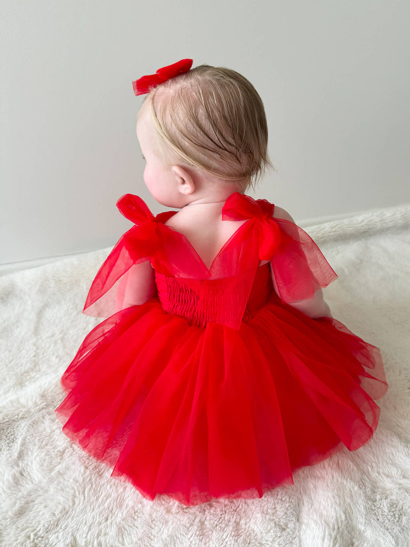 The back of our Harper Christmas baby romper in ruby red, showing the tulle bow straps.