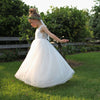 Mia tulle flower girl dress in ivory being worn by a girl who is twirling outside.