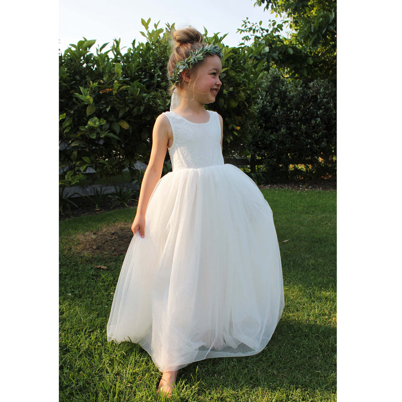 Mia flower girl dress being worn by a girl. Showing the full tulle skirt and sleeveless lace bodice. She also wears our Olive flower crown.