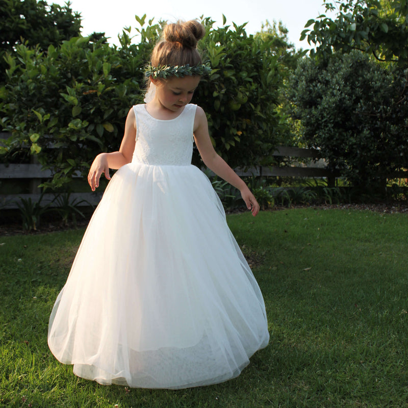 Mia flower girl dress being worn by a young girl. Showing the full tulle skirt and lace bodice. She also wears our Olive flower crown which is a crown of greenery.