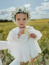 Eva baby flower girl dress with full length tulle sleeves, is worn by a baby girl. She also wears an ivory flower crown.