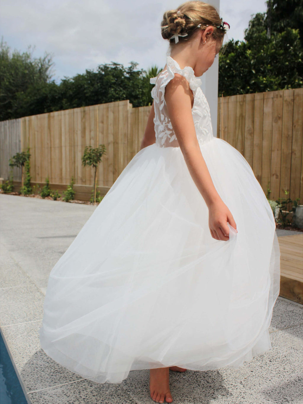 Abigail flower girl dress worn by a young girl. Showing feature lace back and full length tulle skirt.