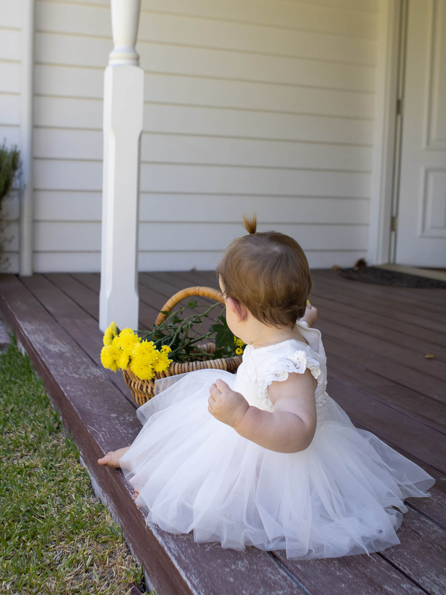 A baby sits in our ivory baby flower girl dress, the Abigail romper dress.
