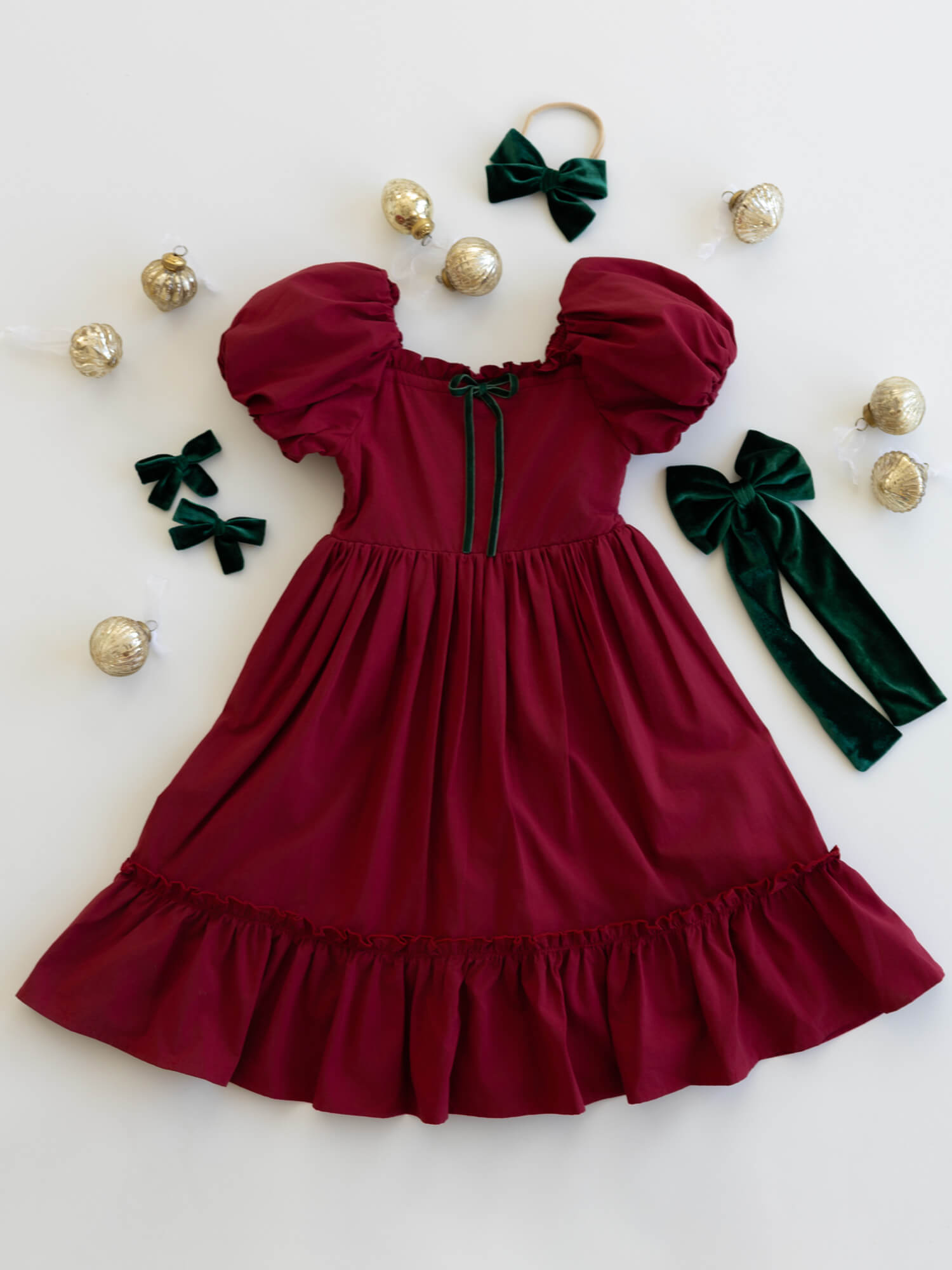 Ava crimson red Christmas dress for girls, with puff sleeves and emerald green bow detail.