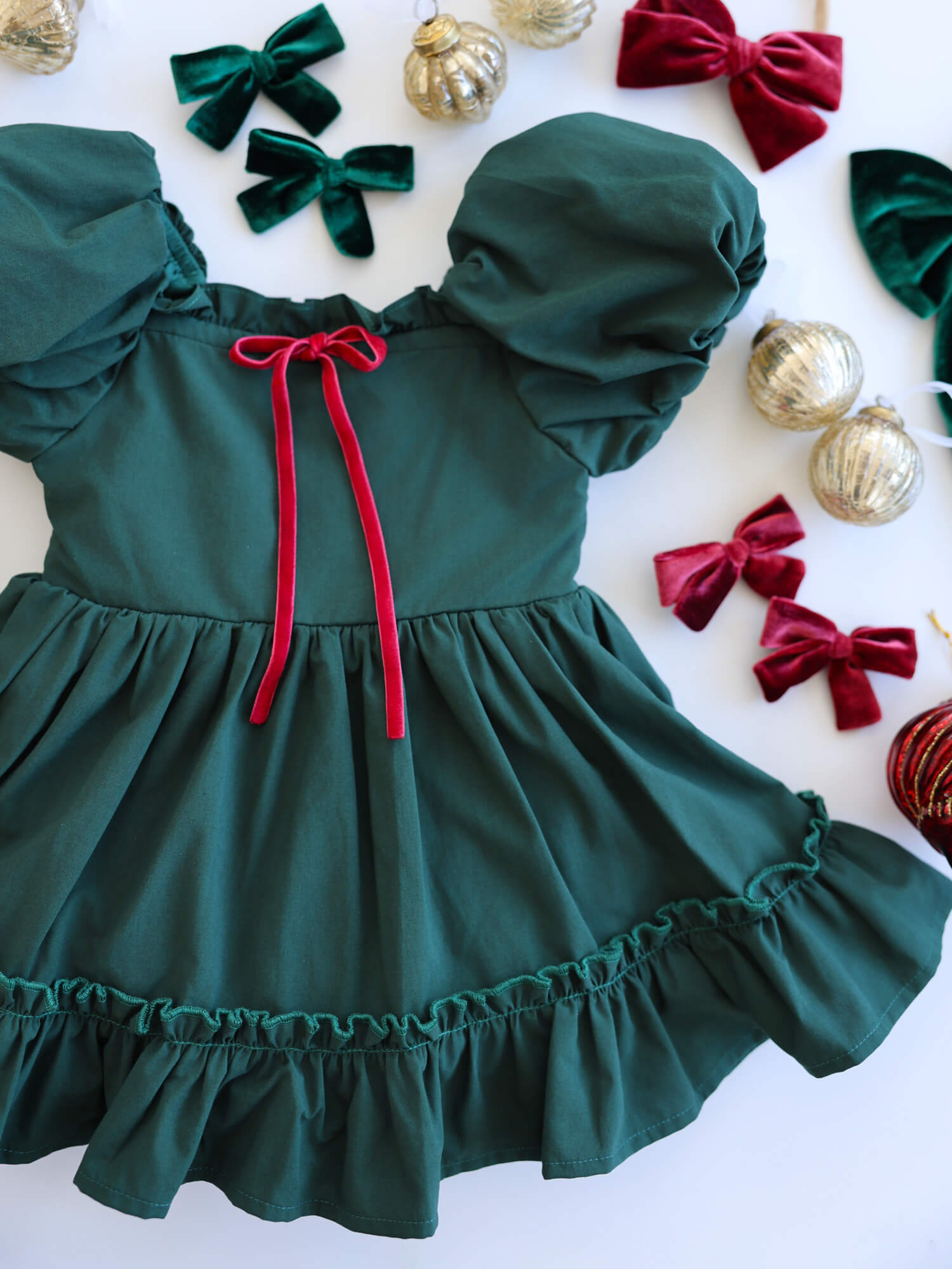 Ava emerald green baby Christmas romper with puff sleeves and velvet bow detail.